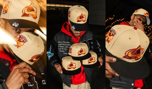 Person holding and displaying a Avalanche beige cap with a logo, wearing a red hoodie.