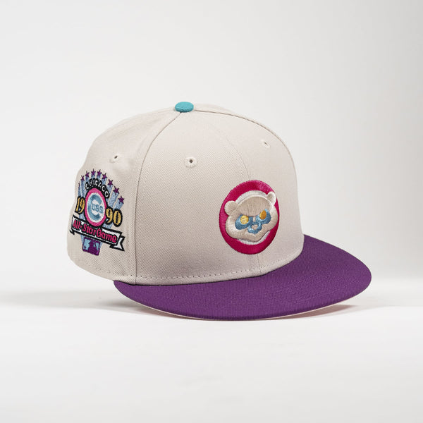 A structured baseball cap with a light beige crown and a contrasting purple flat brim. The crown features a circular embroidered patch on the front with a cartoon bear face inside a pink circle, and a commemorative patch on the side celebrating the 1990 World Series.
