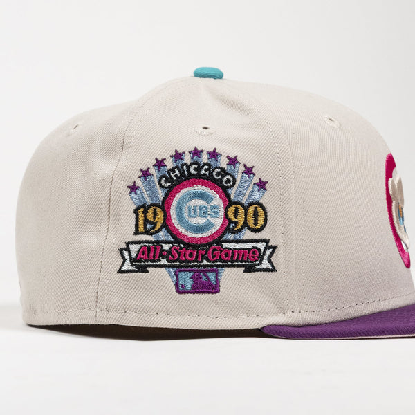 A light beige baseball cap featuring a prominent embroidered Chicago Cubs 1990 All-Star Game patch on the front, with a purple flat brim and a teal button on top.