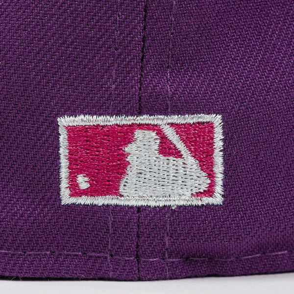Close-up of a purple cap with a logo featuring a white silhouette of a person holding a bat on a pink background. The Pirates Brooklyn 42 ASG 59FIFTY Grape New Era Hat