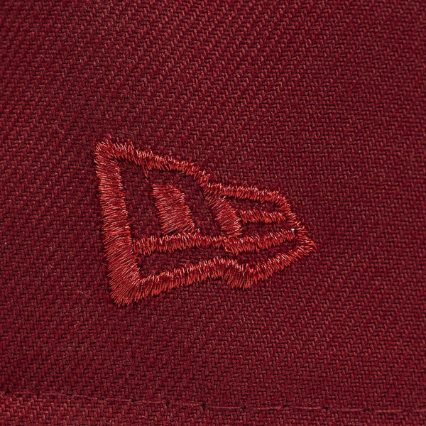 Close-up of a embroidered logo on a maroon fabric background