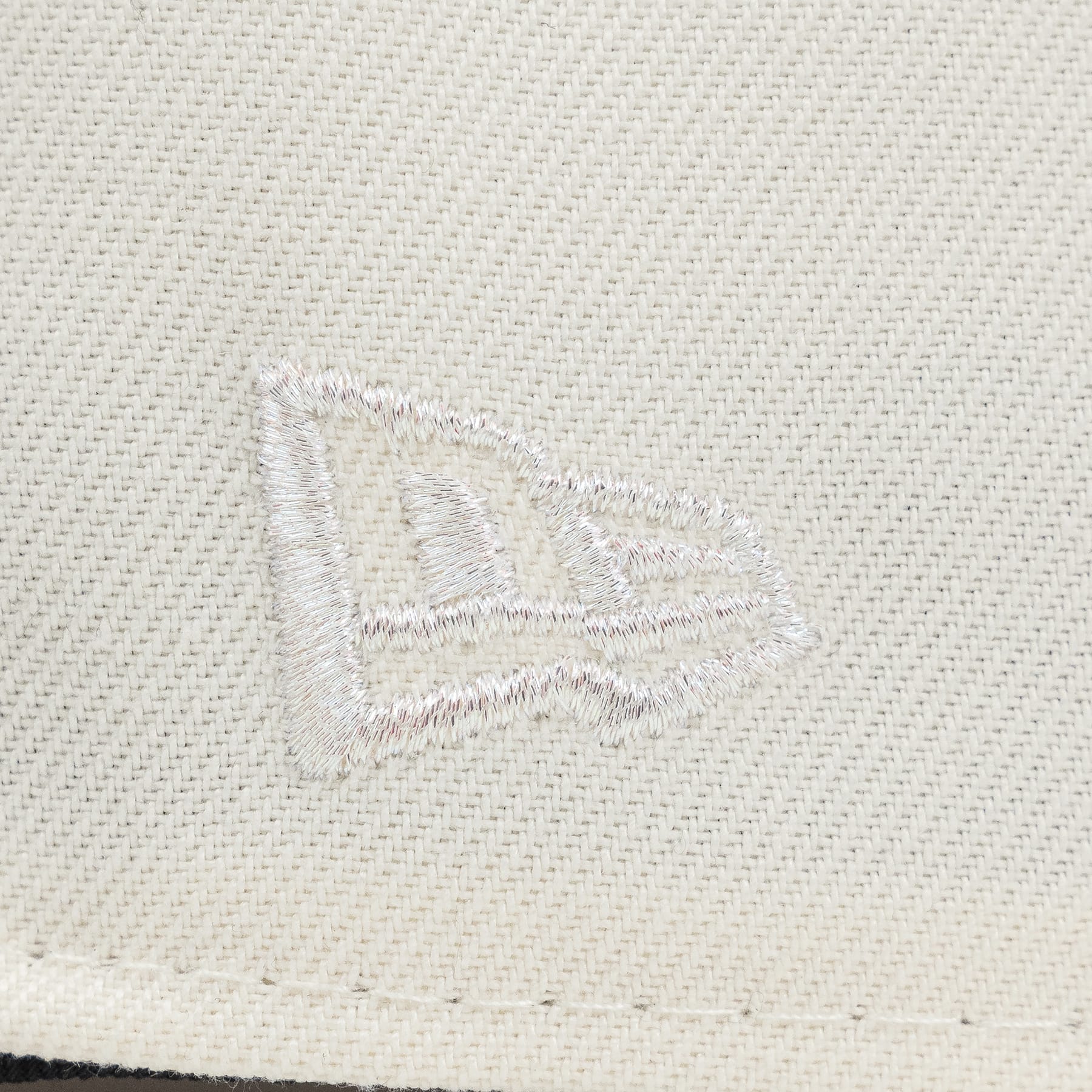 Close-up of a textured fabriThe Pirates Expos 02 ASG 59FIFTY Brick New Era Hat c surface with a logo or emblem.