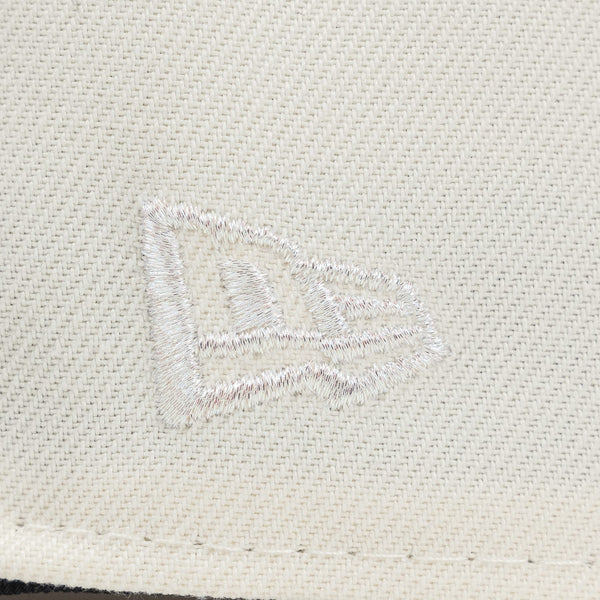 Close-up of a textured fabriThe Pirates Expos 02 ASG 59FIFTY Brick New Era Hat c surface with a logo or emblem.