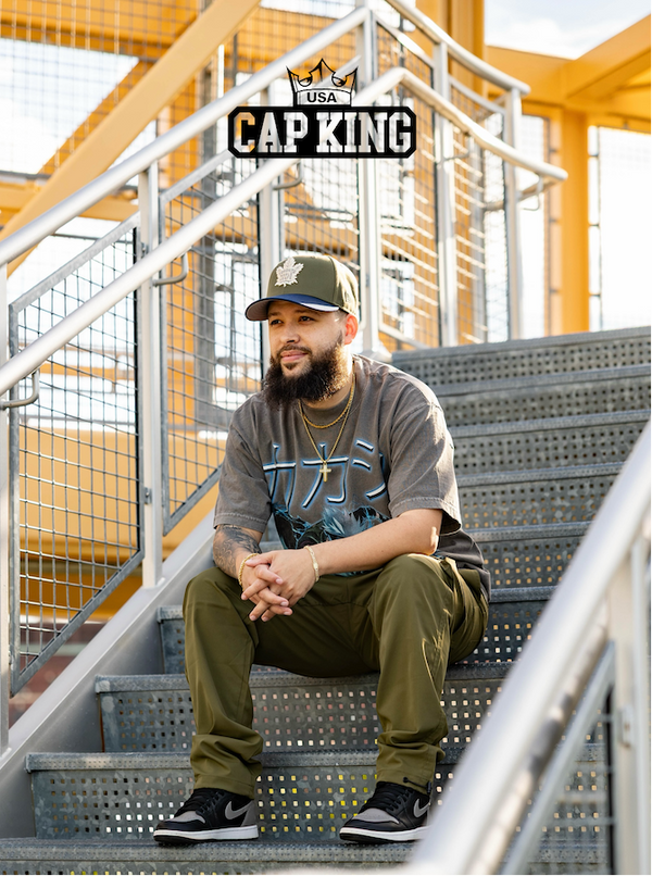 Man sitting on stairs wearing a cap with 'Cap King' logo